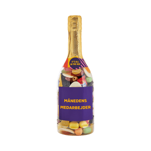 Champagneflaske fyldt med farverigt slik med teksten MÅNEDENS MEDARBEJDER på etiketten. Gaveidé fra SlikEkspressen.