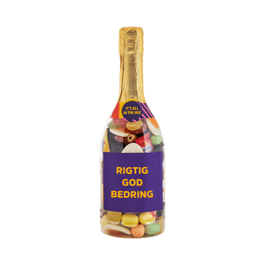 Champagneflaske fyldt med farverigt slik med teksten RIGTIG GOD BEDRING på etiketten. Gaveidé fra SlikEkspressen.
