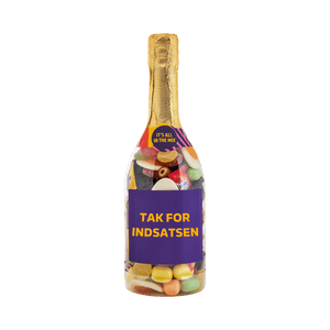 Champagneflaske fyldt med farverigt slik og teksten TAK FOR INDSATSEN på etiketten. Gaveidé fra SlikEkspressen. 