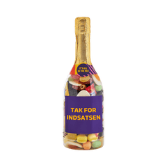 Champagneflaske fyldt med farverigt slik og teksten TAK FOR INDSATSEN på etiketten. Gaveidé fra SlikEkspressen. 