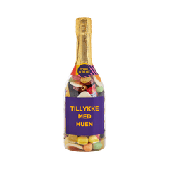Champagneflaske fyldt med bland selv-slik og lilla etiket med teksten "Tillykke med huen" – perfekt gave til studenten fra SlikEkspressen.
